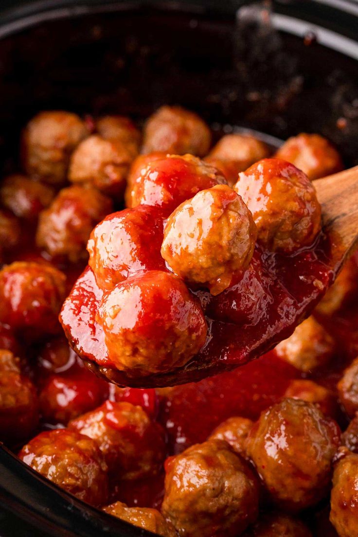 a wooden spoon full of cranberry meatballs with ketchup on top