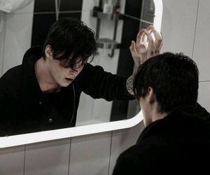 a man is looking at his reflection in the mirror