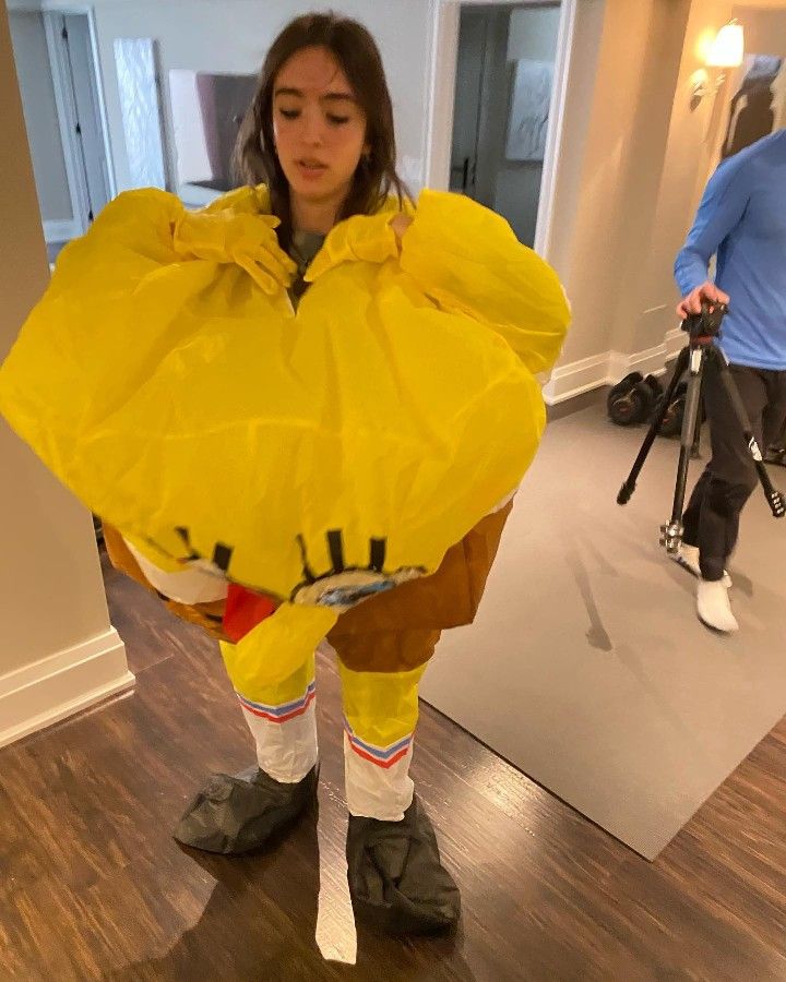 a woman in yellow raincoat and rubber boots standing on wooden floor next to man