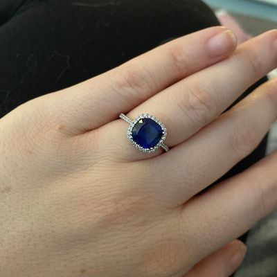 a woman's hand with a ring on it and a blue stone in the middle