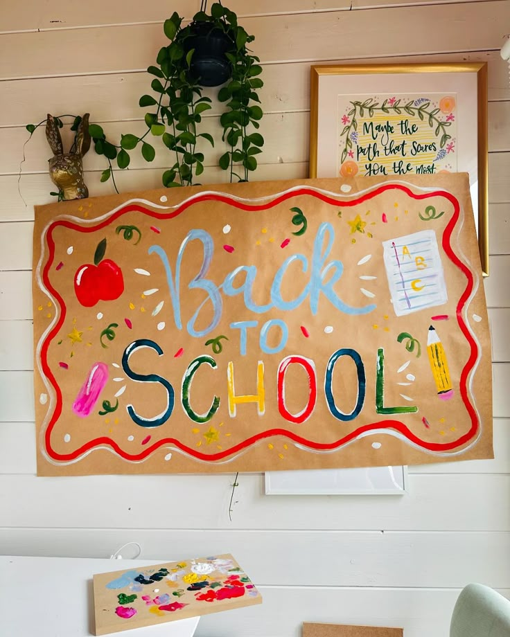 a back to school sign hanging on the side of a wall next to a potted plant