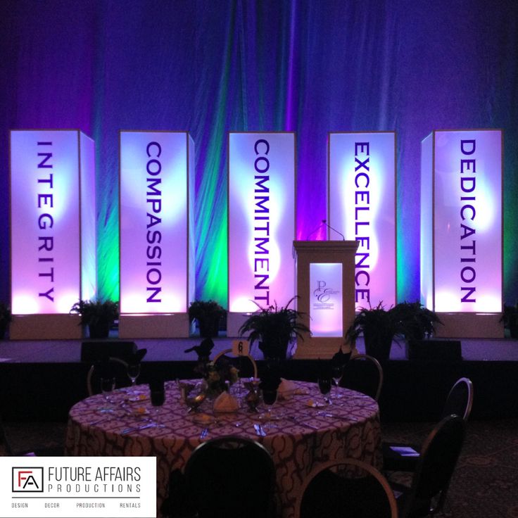 a stage set up for an event with purple and green lighting on the side wall