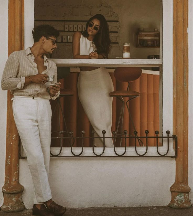 a man and woman standing in front of a bar with orange bars on the windowsill