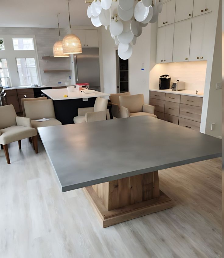 a modern kitchen with an island and dining room table in the center, surrounded by beige chairs