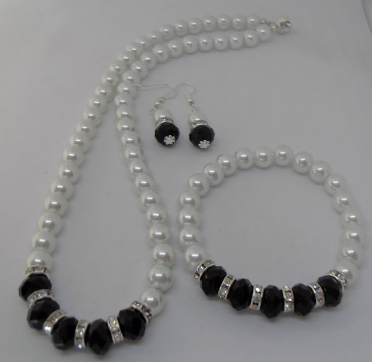 This is a beautiful classic white Czech glass pearl necklace, earrings and bracelet set. The white pearls, black faceted crystals and silver diamante spacers are all 8 mm.  The clasp is silver plated and magnetic making it easy to take on and off.  The necklace is approximately 18 ins long and the bracelet is on jewellers elastic  and fits most wrists. Please get in touch if you require a smaller or larger necklace or bracelet as I make to order.  The earrings are silver plated dangle earrings. Please note: If you require different coloured faceted glass crystals or pearls beads please get in touch as I have many other colours available. White Pearl Jewelry With Black Beads, Glass Bead Bracelet Patterns, Jewelry Necklace Simple, Pretty Jewelry Necklaces, Pearl Necklace Set, Pearl Necklace Earrings, Thread Jewellery, Pearl Jewelry Sets, Beads Bracelet Design