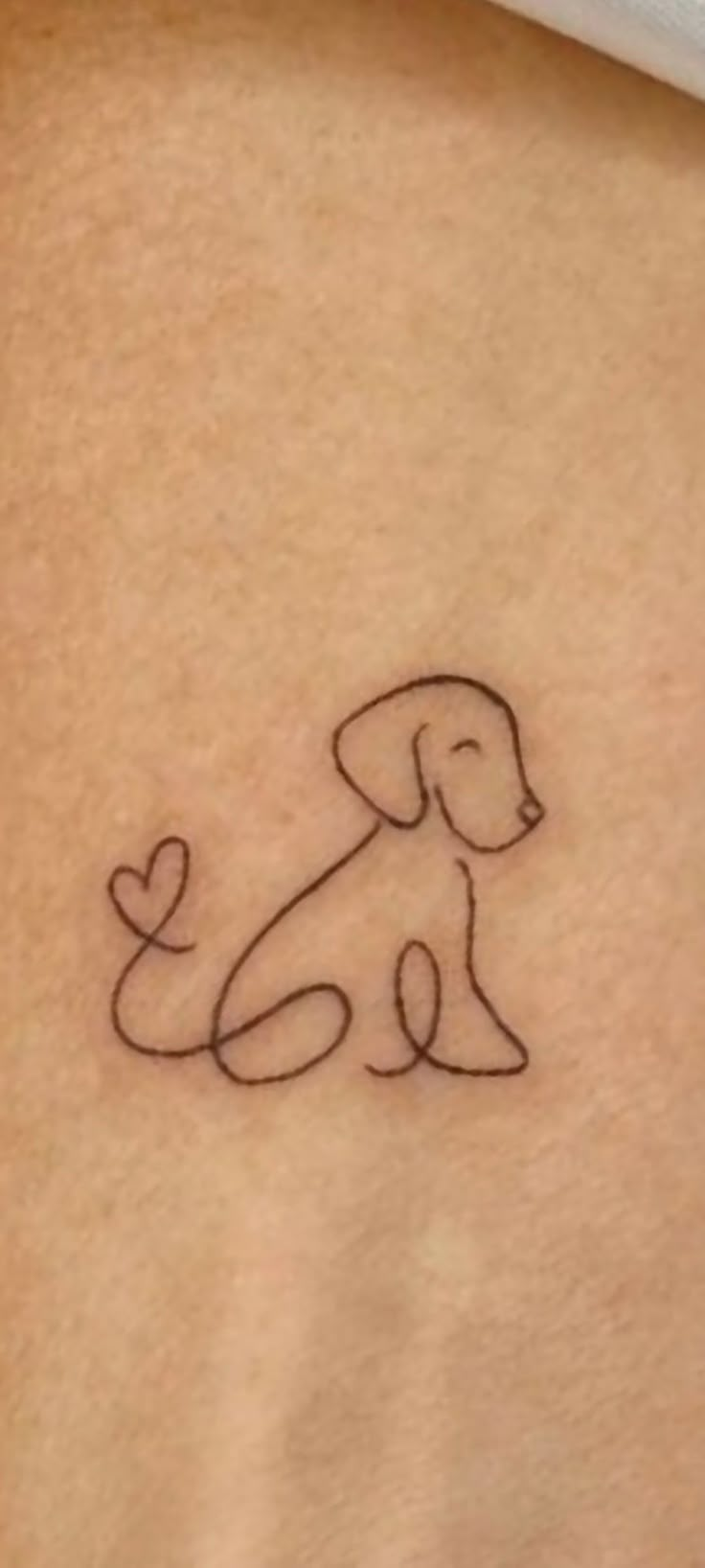 a small dog tattoo on the back of a woman's stomach