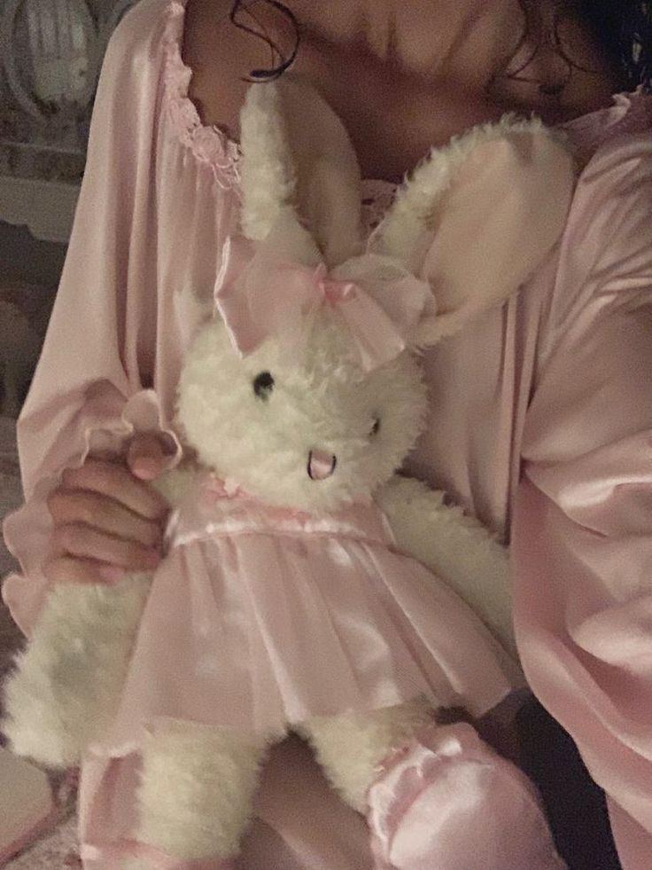 a woman in pink pajamas holding a white stuffed animal