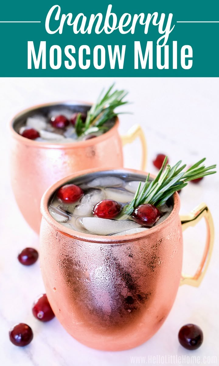 two cranberry moscow mules in copper mugs with rosemary garnish