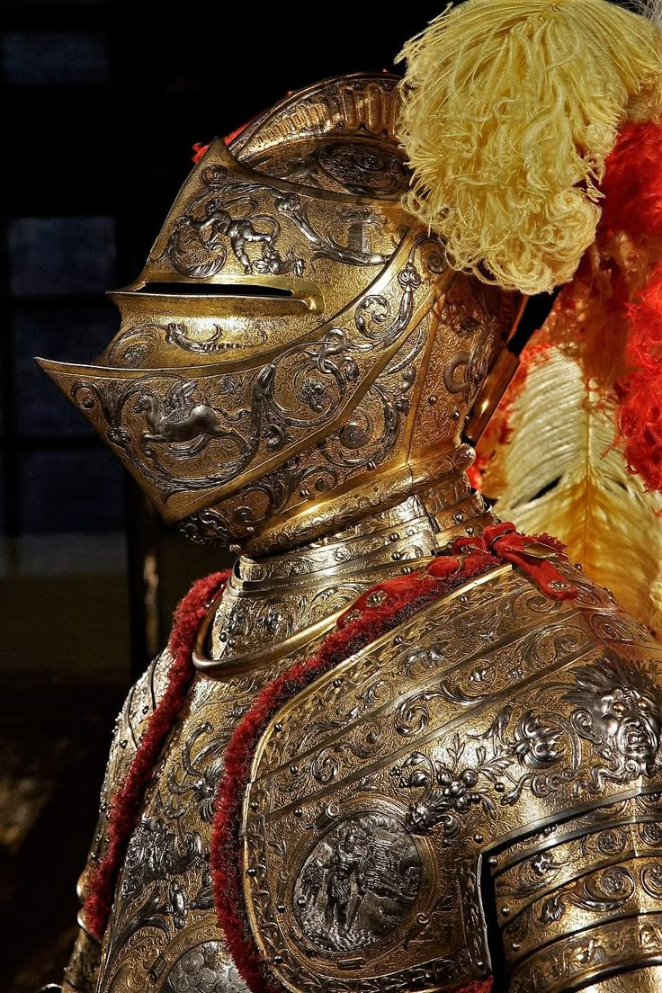 a teddy bear dressed as a knight in gold armor and red flowers on his chest