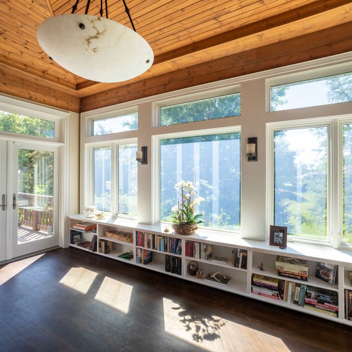 the sun shines through three large windows in a room with bookshelves and open doors