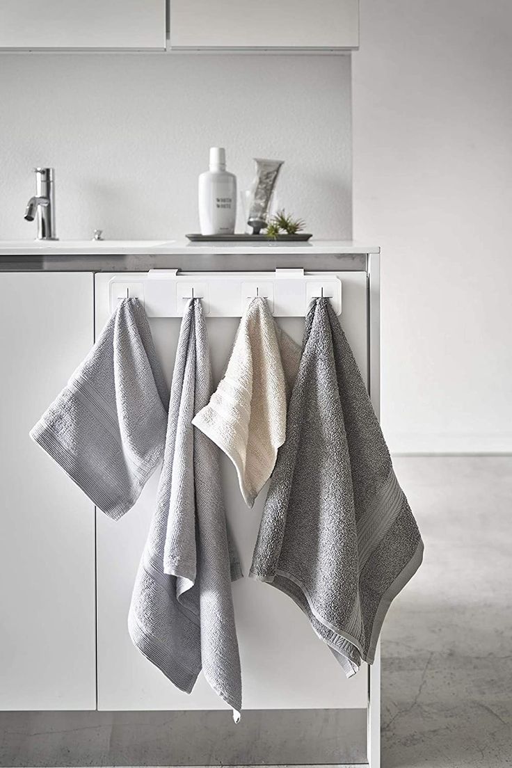 two towels hanging on the side of a white cabinet