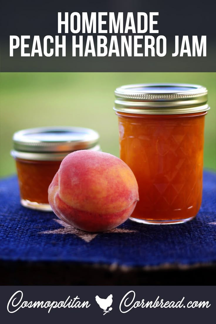 two jars filled with peach jam sitting on top of a blue cloth next to an apple