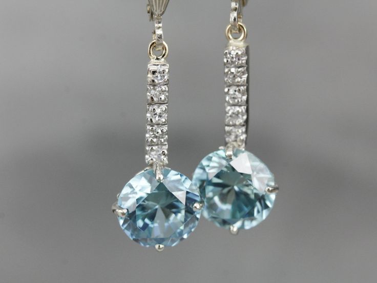 "These lovely zircons are bright and bold! The color is cool, luscious sky blue, with plenty of sparkles! The long bar at the center is inlaid with sparkling diamonds, at the very top are the earring wires, hinged lever backs which are brand new, 14K white gold with a simple polished design. These are comfortable to wear and very secure! Metal: 14K White Gold Gem: 2 Blue Zircon totaling 6.81 Carats Gem Measurements: 8.2 mm, Round Accents: 10 Diamonds totaling .10 Carats, F in Color, VS in Clarit Blue Diamond Earrings With Diamond Cut, Blue Diamond Cut Earrings, Dazzling Blue Earrings With Diamond Accents, Luxury Blue Aquamarine Earrings, Luxury Aquamarine Blue Earrings, Dazzling Blue Diamond Earrings, Blue Diamond Earrings With Sparkling Stones, Drop Earrings Bridal, White Gold Drop Earrings