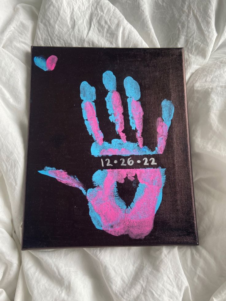 a hand print on a black canvas with blue and pink paint