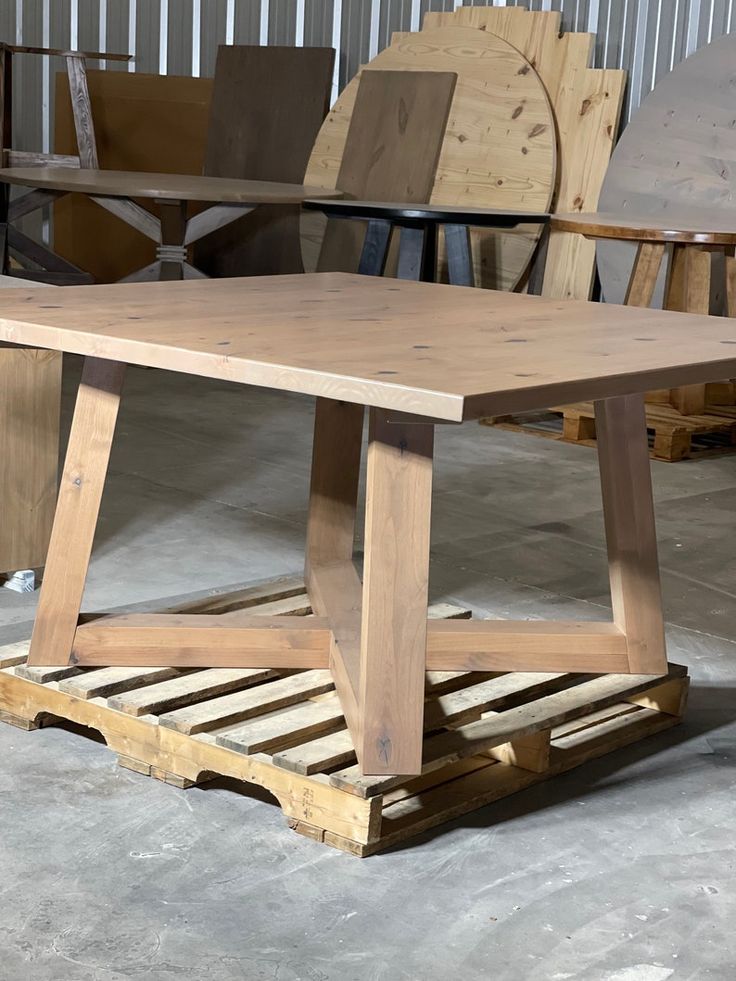 a wooden table sitting on top of a pallet next to some chairs and tables