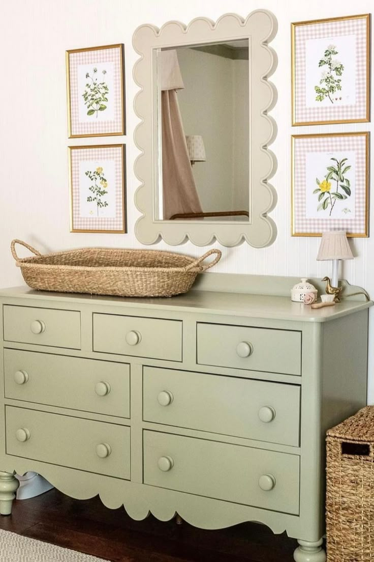 a dresser and mirror in a room with pictures on the wall