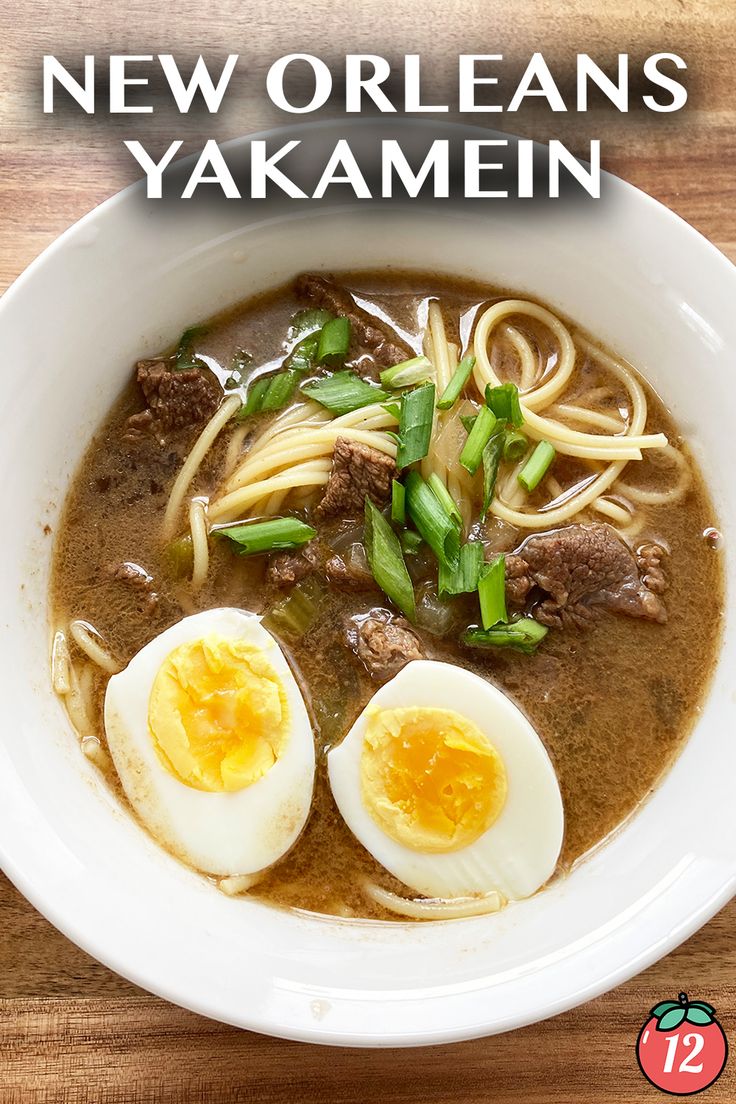 a white bowl filled with noodles, meat and hard boiled eggs on top of a wooden table