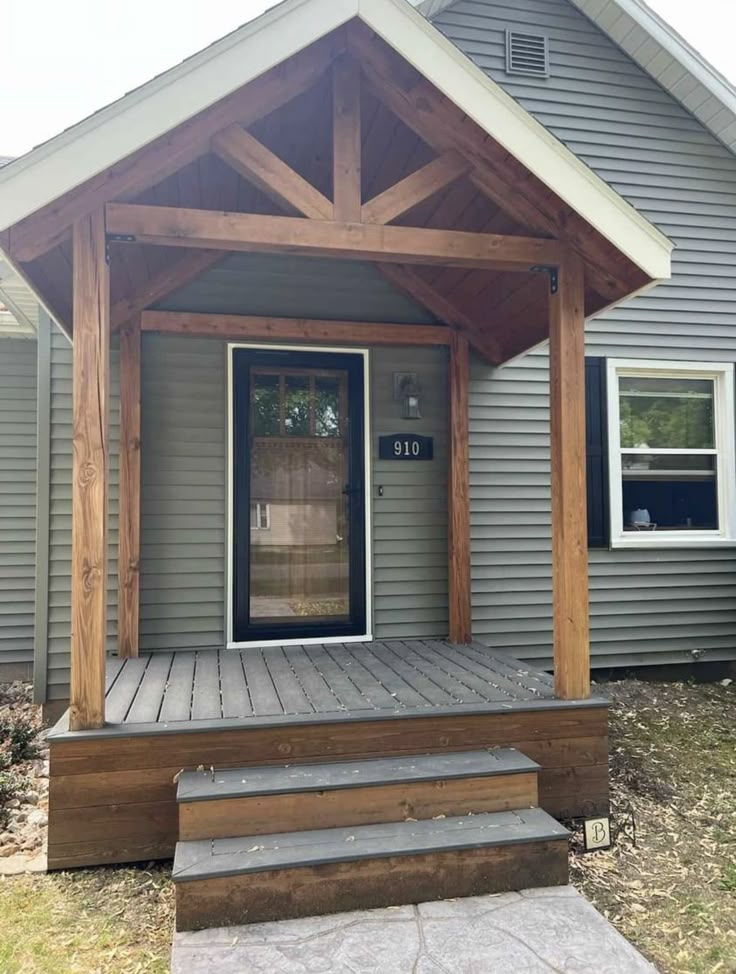 a porch with steps leading up to the front door and covered in wood planks