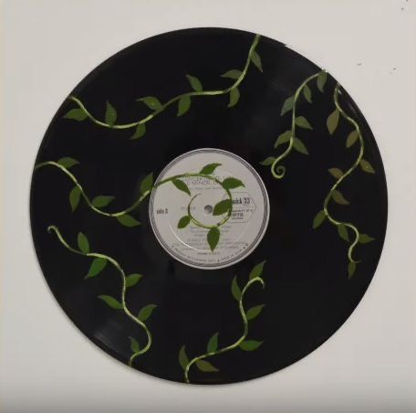 a black record with green leaves on the front and back side, in a white frame