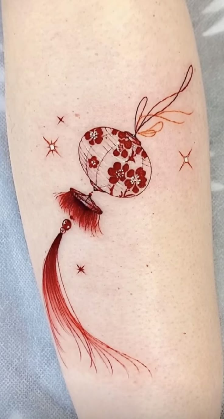 a woman's leg with a tattoo on it that has flowers and a fan