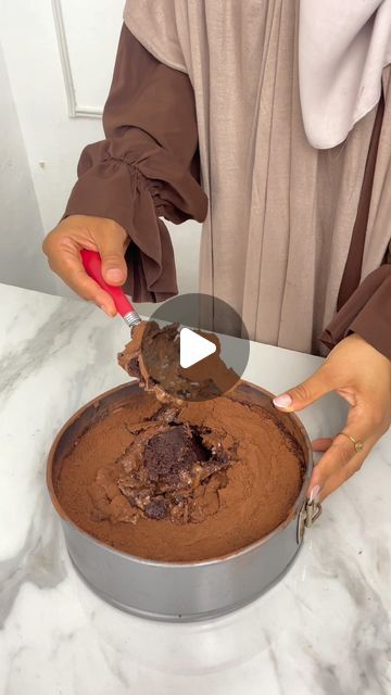 a woman is cutting into a chocolate cake