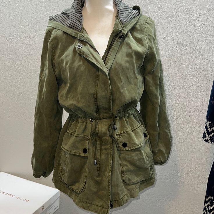 Army, Green Sanctuary Drawstring Lined With Oversized Pocket, Zip, And Button Jacket This Jacket Is Size, Small But Definitely Has An Oversize Fit Can Work For A Medium As Well Great Black And Gray, Striped Lining Accent On The Hood And Interior Lighting As Well As The Pockets. Plenty Of Space For All The Things. Utility Outerwear For Winter Layering, Casual Long Sleeve Outerwear With Drawstring, Casual Winter Outerwear With Drawstring, Casual Drawstring Winter Outerwear, Fall Utility Long Sleeve Parka, Fall Utility Parka With Long Sleeves, Fall Workwear Outerwear With Drawstring, Winter Cotton Outerwear With Drawstring, Casual Green Utility Jacket For Fall