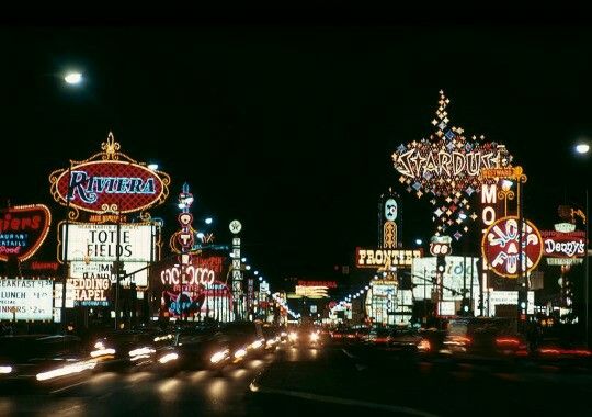 the neon signs are lit up at night in las vegas, nv on this busy street