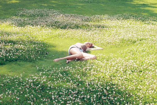 a woman laying on the ground in a field of flowers