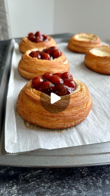 croissants with cherries on top sitting on a baking sheet