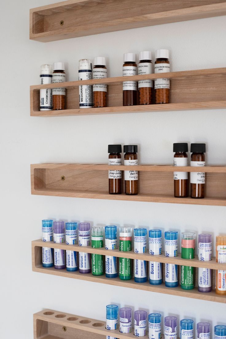 the shelves are filled with many different types of medicine bottles on them, and one shelf is made from wood