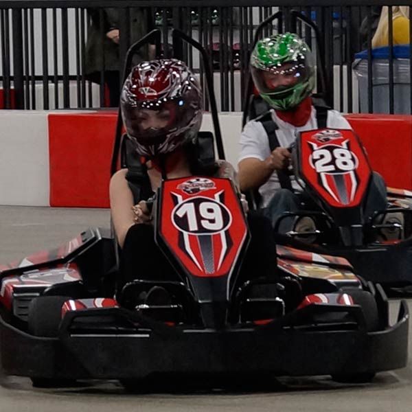 two people in go kart racing cars with helmets on