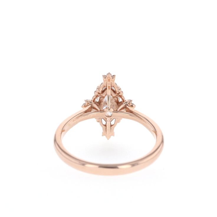 a rose gold ring with an oval shaped diamond in the center and two small diamonds on each side