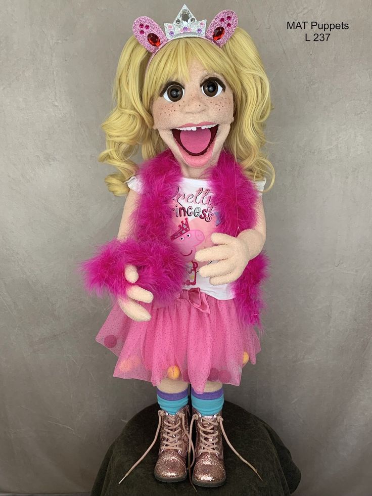 a doll with blonde hair wearing a pink dress and tiara on top of a rock