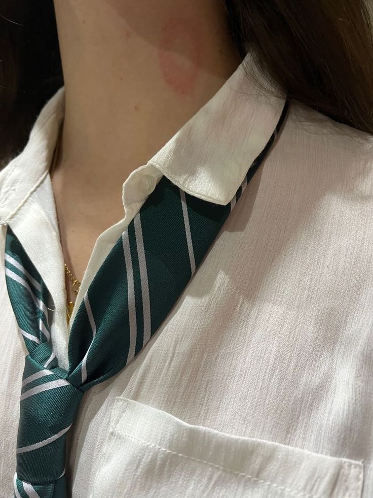 a woman wearing a white shirt with a green striped neck tie on her collared