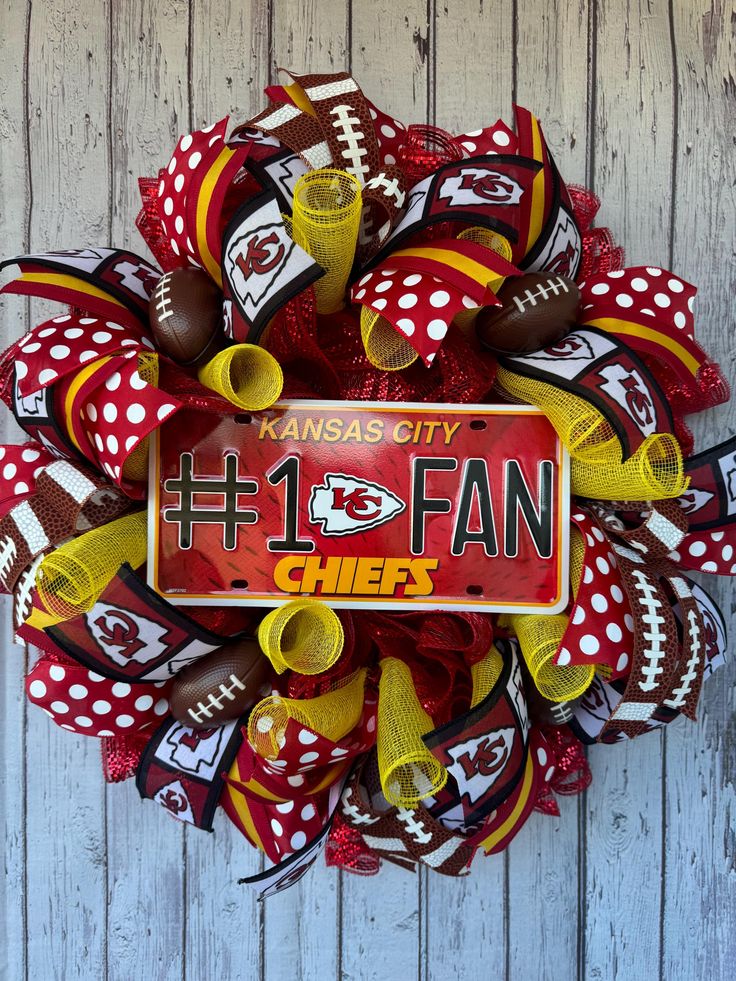 a football themed wreath with the number one fan on it, decorated in red and yellow