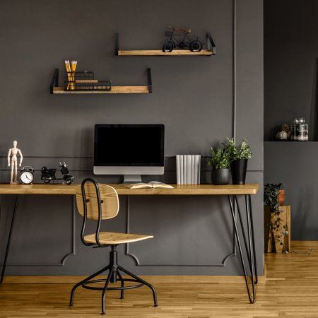 a computer desk with two pictures on the wall above it and a chair in front of it