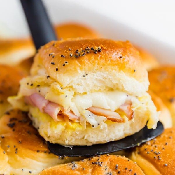 ham and cheese sliders in a white bowl with a black plastic fork on top