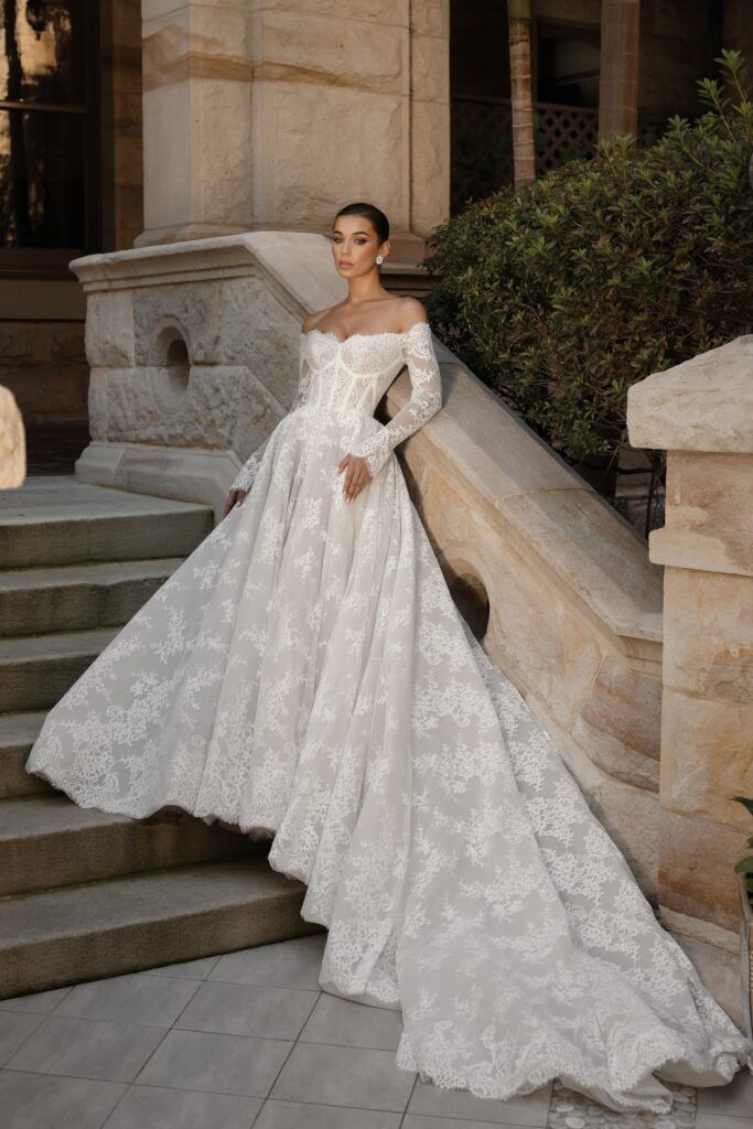 a woman in a white wedding dress standing on some steps with her hand on her hip