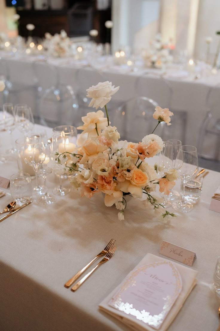 the table is set with white and orange flowers, silverware, and place settings