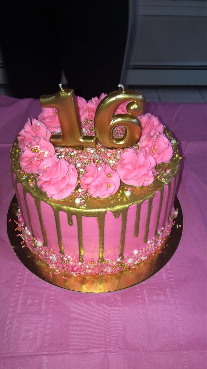 a pink and gold birthday cake with flowers on it