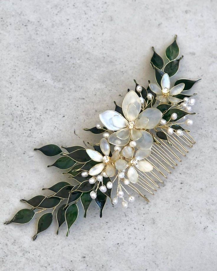 a close up of a hair comb with flowers and leaves on the front, sitting on a marble surface