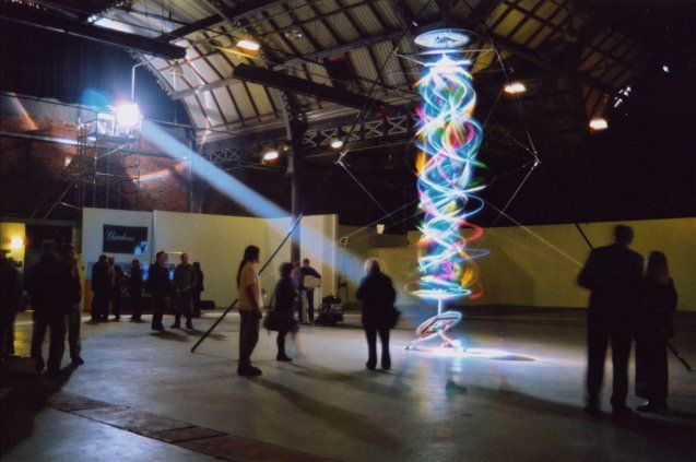 a group of people standing around in a room with lights on the ceiling and one person holding a camera