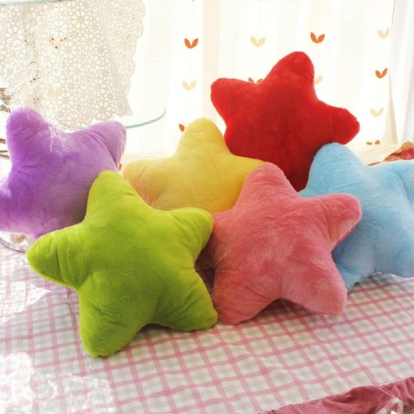 four star shaped pillows on a table with pink, blue, green and yellow checkered cloth