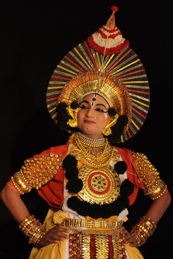 a woman dressed in an elaborate costume and headdress, standing with her hands on her hips