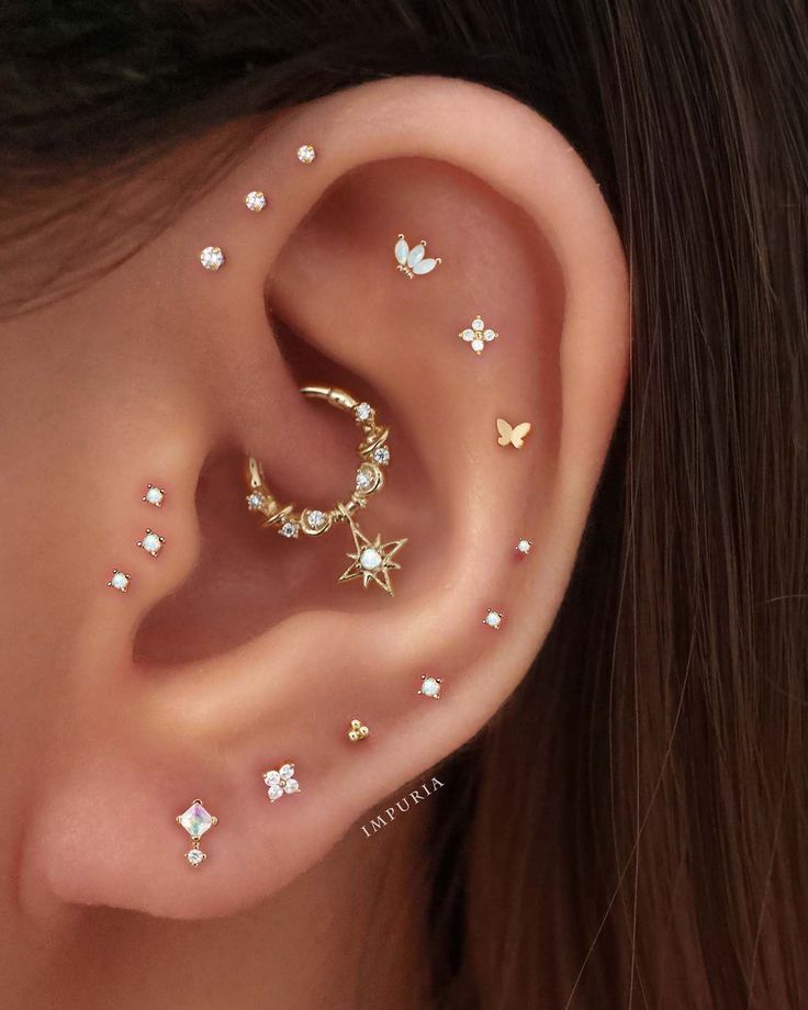 a woman's ear is adorned with gold and white stars, which are attached to the side of her ear