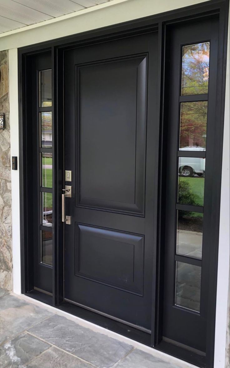 a black front door with two sidelights and glass panels on the outside of it