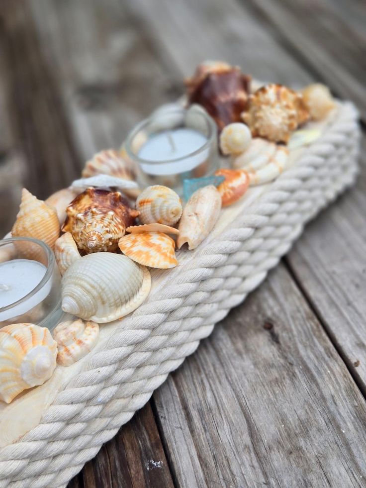 sea shells and candles sit on a rope tray