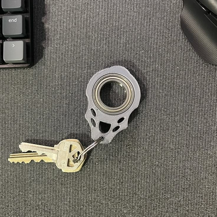 a pair of keys sitting on top of a computer keyboard next to a keychain