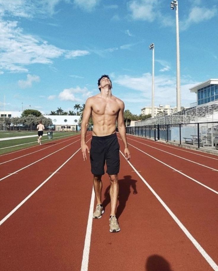 a shirtless man is walking on a track