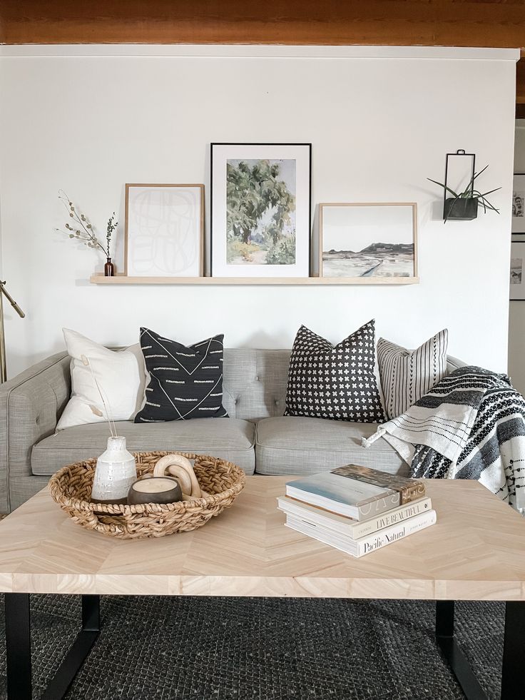 a living room filled with furniture and pillows on top of a wooden table in front of a white wall